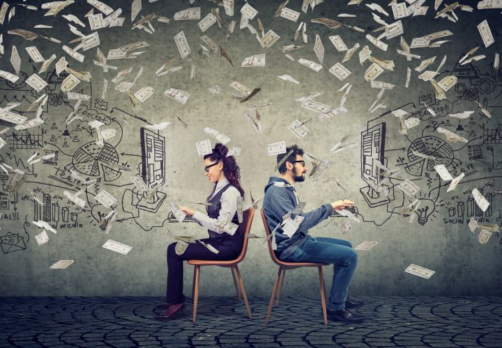 Business man and businesswoman working on computer developing successful strategy under money rain