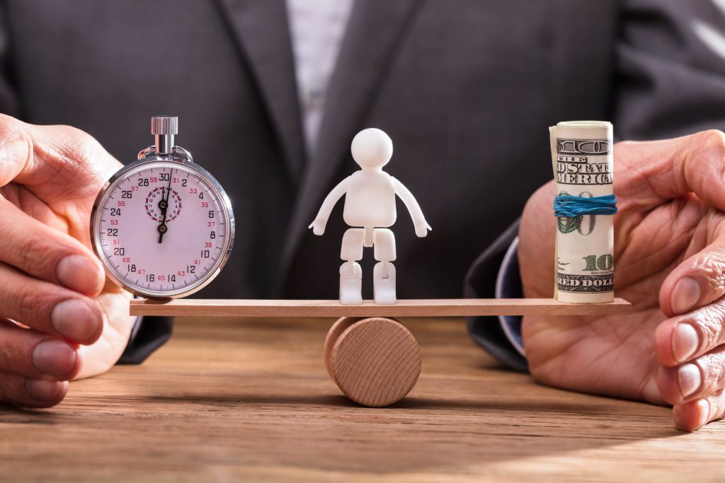 toy man balancing between a clock and a roll of money with the hands of a registered agent helping him